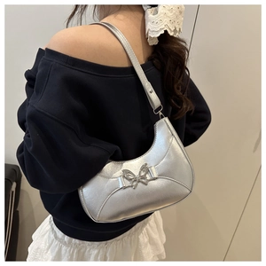 Sac hobo demi-lune argenté métallisé avec fermoir papillon porté à l'épaule par un mannequin