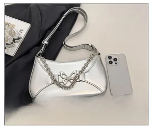 Detailed view of silver butterfly chain bag next to phone for size comparison
