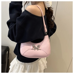 Détail du sac croissant rose avec boucle papillon argentée porté à l'épaule