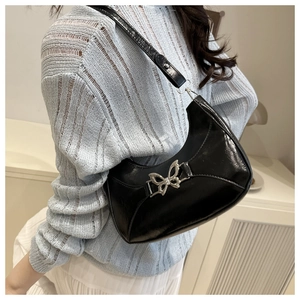 Gros plan sur le sac à bandoulière en cuir verni noir avec boucle papillon argentée