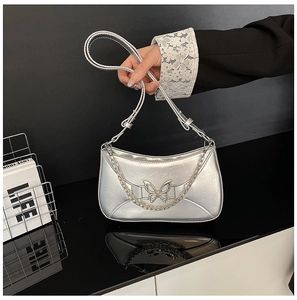 Détail du sac hobo argenté avec boucle papillon métallique et chaîne décorative