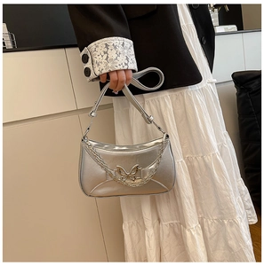 Détail du sac hobo argenté avec boucle papillon et chaîne décorative chic