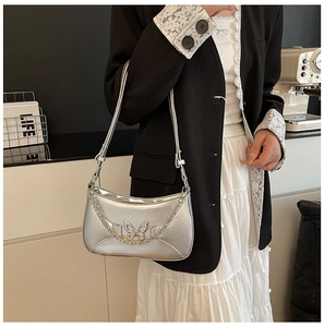 Détail du sac argenté métallisé avec pendentif papillon évidé et fine chaînette
