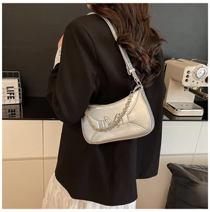 Détail du sac baguette argenté métallisé avec relief papillon et chaîne à l'épaule