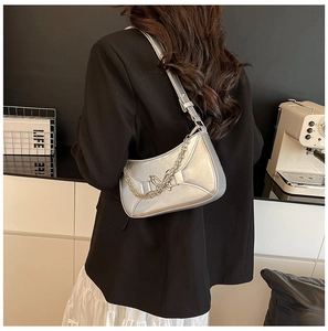 Détail du sac sous le bras argenté métallisé avec chaîne papillon sur costume noir