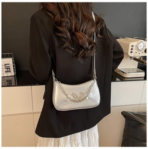 Détail du sac demi-lune argenté avec boucle papillon en métal et détails de la chaîne