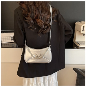 Detail of silver crescent bag with metallic butterfly buckle and chain strap on model