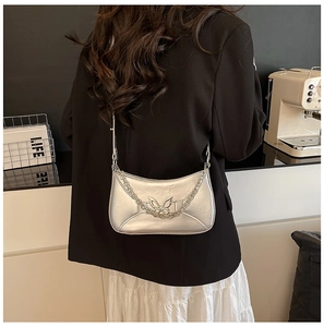 Détail du sac hobo argenté avec boucle papillon et chaîne métallique sur mannequin