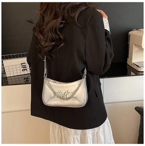 Détail d'un sac à bandoulière en cuir argenté avec boucle décorative en papillon
