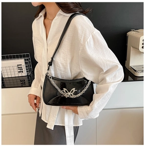 Détail du sac d'épaule en cuir verni noir avec boucle papillon argentée et chaîne