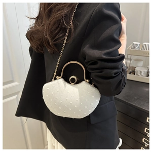 Detailed view of silver beaded heart evening bag with gold handle and chain strap