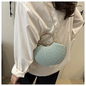 Detail of mint green saddle bag with gold ring closure and chain on white outfit
