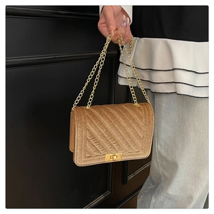Gros plan du sac bandoulière en velours camel avec matelassage en V et chaîne dorée