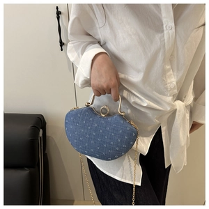Detail of navy denim evening clutch with white letter pattern and gold metal ring clasp