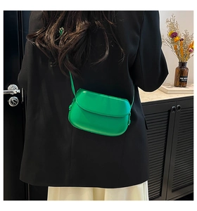 Vue détaillée d'un sac à main vert vif porté avec une veste de costume noire moderne
