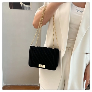 Détail du sac bandoulière en velours noir avec chaîne dorée et motif matelassé