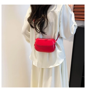 Vue arrière du mannequin portant un petit sac bandoulière rouge sur tenue blanche