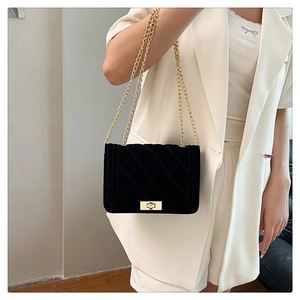 Detail einer schwarzen Stepptasche mit goldener Kette und Metallschloss an einem Model