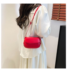 Vue détaillée du sac selle rouge sur tenue blanche avec ombre et lumière naturelle élégante