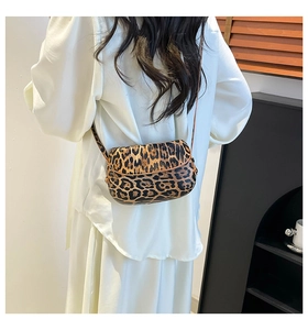 Détail d'un sac besace à imprimé léopard porté avec une tenue d'été blanche chic