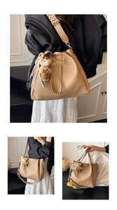 Detail of khaki tote bag with wide geometric strap and plush bear charm for daily use
