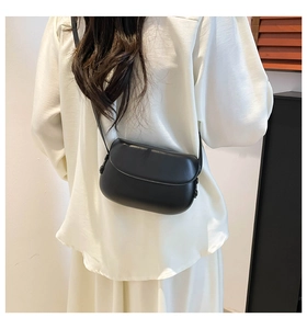 Rear view of a black leather saddle bag with flap cover worn by a model