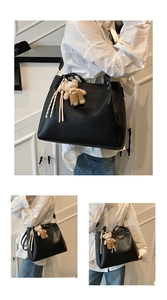 Close-up of black lychee grain leather tote bag with cute plush bear charm detail
