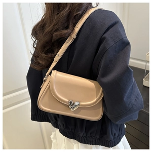 Side view of a beige PU leather crossbody bag with a silver heart buckle on a model