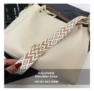Close-up of adjustable zigzag patterned shoulder strap with golden metal buckle on cream bag