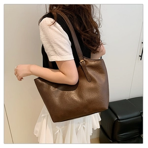 Detail of vintage dark brown tote bag with aged leather texture and adjustable strap