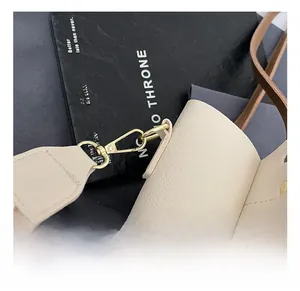 Macro shot of gold metal swivel hook and brown leather strap on beige textured tote bag