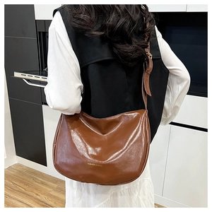 Back view of model wearing a vintage brown faux leather tote bag with gold lettering