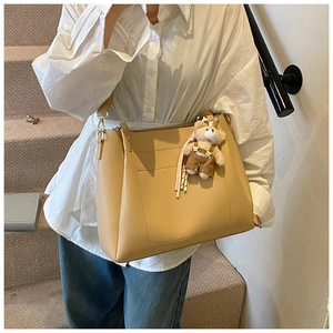 Close-up of khaki tote bag with plush bear charm and practical front pocket