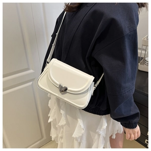 Detailed side view of a white leather crossbody bag with silver heart-shaped metal buckle