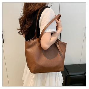 Brown vintage tote bag with textured faux leather shown worn over the shoulder by a model