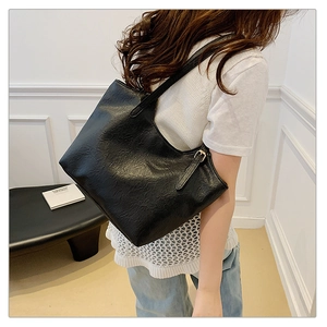 Detail of vintage black tote bag showing textured PU leather and metallic buckle details