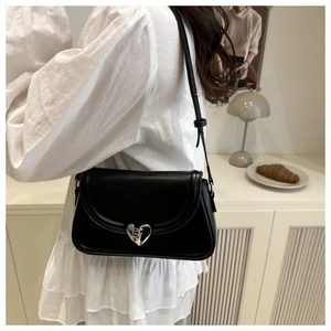 Close-up of black crossbody bag with silver heart-shaped lock on a matte flap design