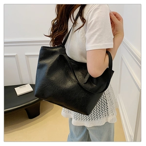 Detail shot of the black oil-wax PU leather tote bag on a model with long shoulder straps