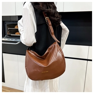 Brown oil wax leather crescent shoulder bag with golden text shown on a model