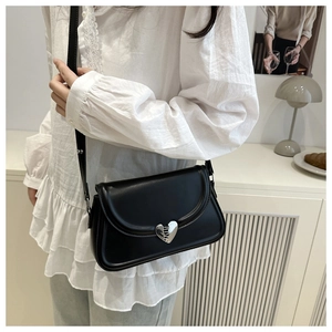 Detail shot of a black square crossbody bag featuring a silver heart-shaped metal buckle