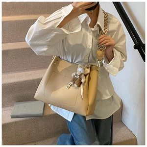 Detailed view of beige faux leather tote bag with wide geometric strap and bear charm
