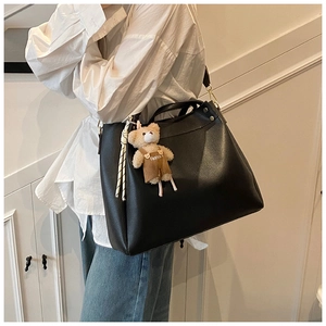 Detail of black tote bag with plush bear charm and knotted tassel decoration