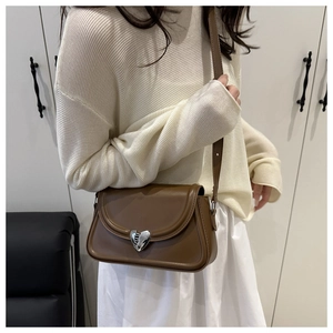 Close-up of a vintage brown crossbody bag with a silver heart-shaped textured metal lock