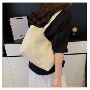 Detailed side view of a large cream white tote bag with textured faux leather on a model