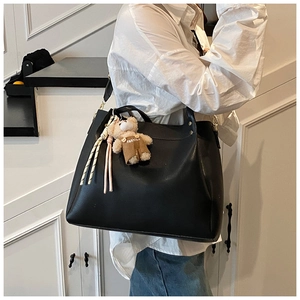 Detailed shoulder view of a black large capacity tote bag with cute bear charm decoration