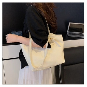 Close-up of cream white leather tote bag with litchi texture and metal buckle detail