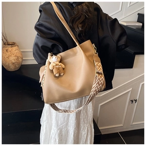 Detailed view of camel tote bag with bohemian geometric strap and bear charm pendant
