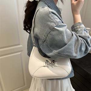 Sac hobo blanc en similicuir avec boucle papillon argentée porté par un mannequin