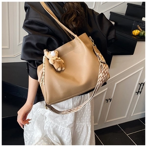 Detail of khaki leather tote with detachable geometric strap and bear charm