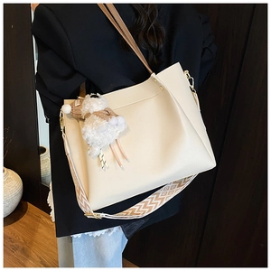 Detail of cream tote bag with dual straps and cute sheep charm in lifestyle setting
